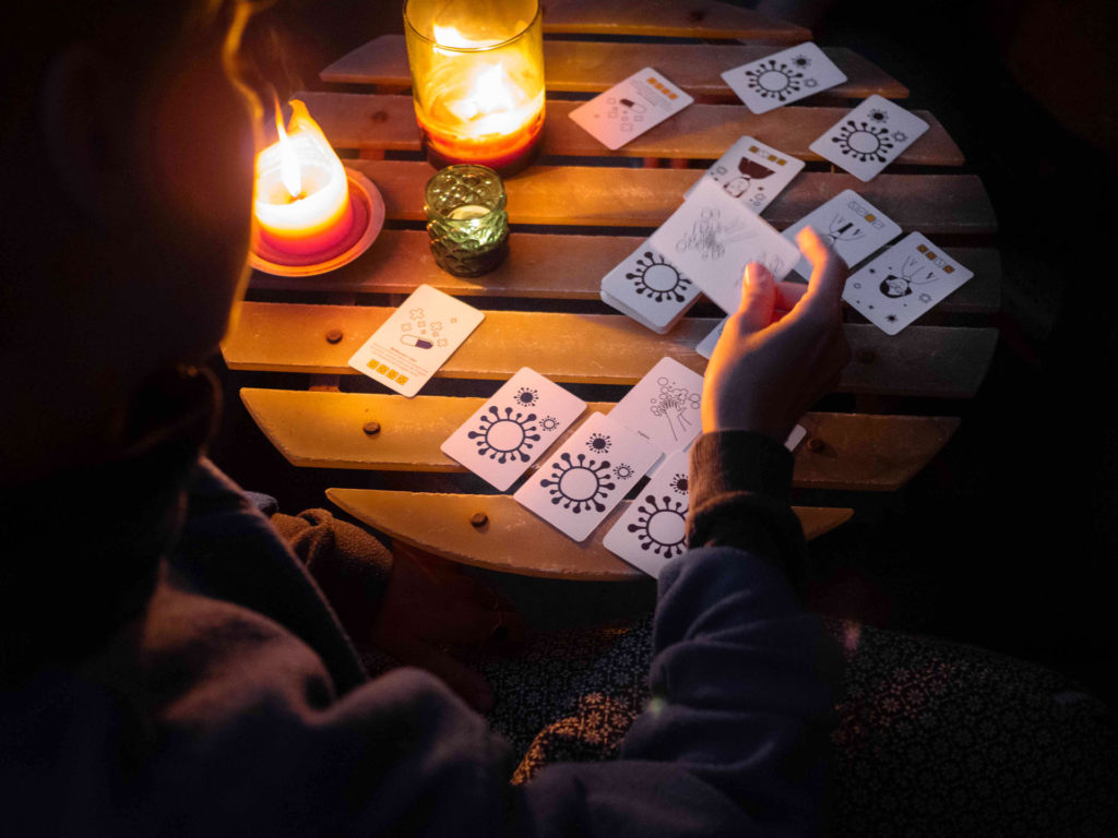 Es ist dunkel. Zwei Personen spielen Karten auf einem Balkon.